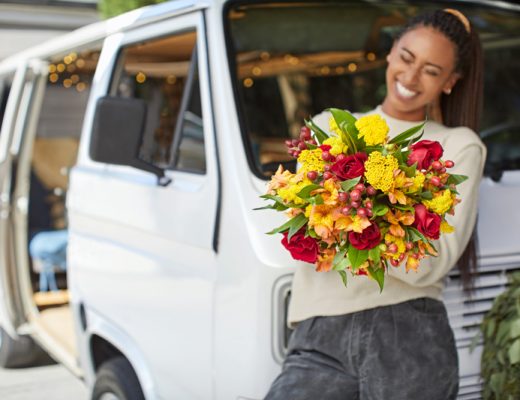 Woman holding fresh bouquet of yellow, red and green flowers