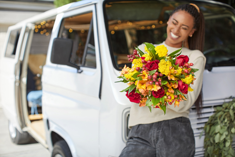 Woman holding fresh bouquet of yellow, red and green flowers