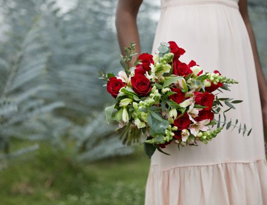 woman holding a bouquet of red roses with greenery