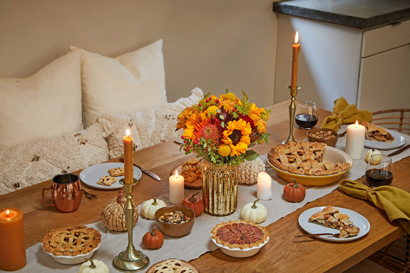 orange yellow fall centerpiece at dinner table with pumpkin pie