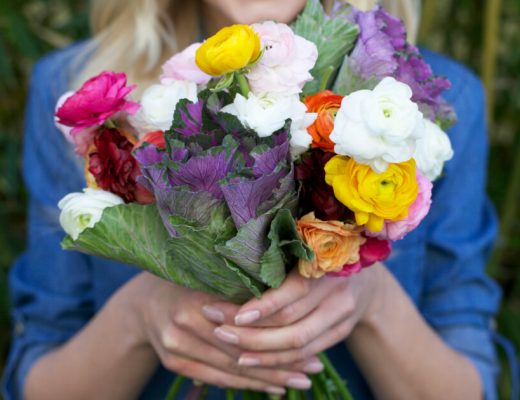 Woman holding a bouquet of flowers including ranunculus.