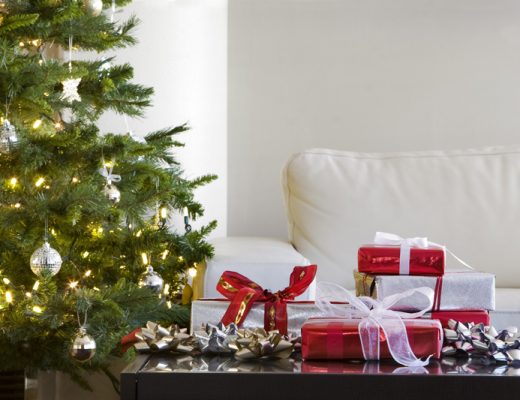 live christmas tree next to presents on a table in a modern living room