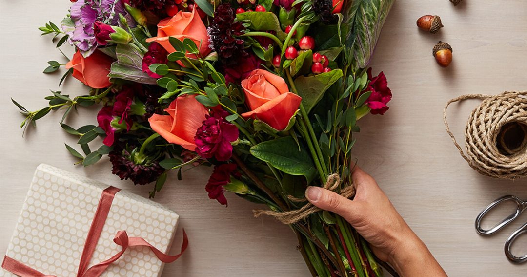 peachy coral roses bouquet next to a present