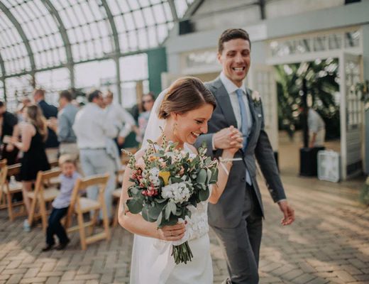 bride walking down the aisle holding a bouquet with yellow and red and white flowers