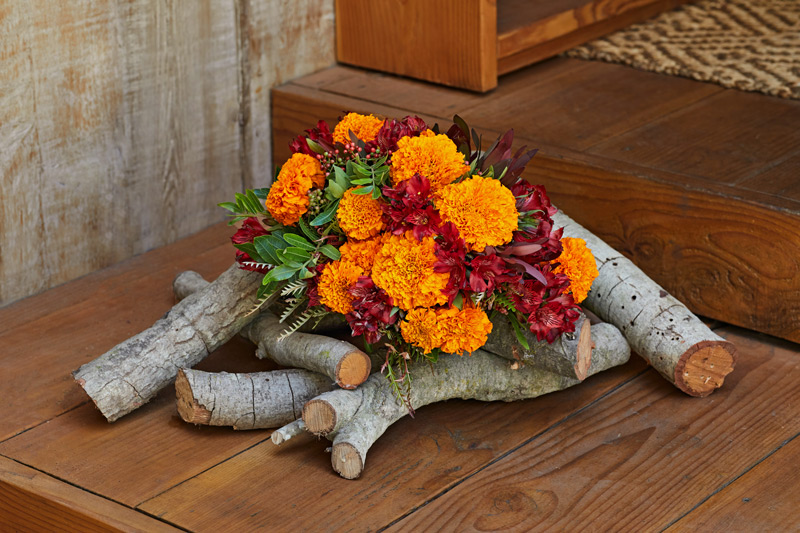 Red and orange flower bouquet display over firewood logs for a rustic arrangement