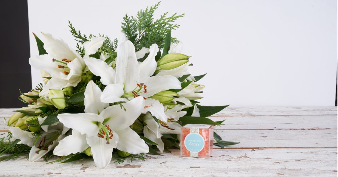 White Lilies in a Bouquet with Orange Sugarfina Champagne Bears in a Clear Box Gifts for Co-Workers