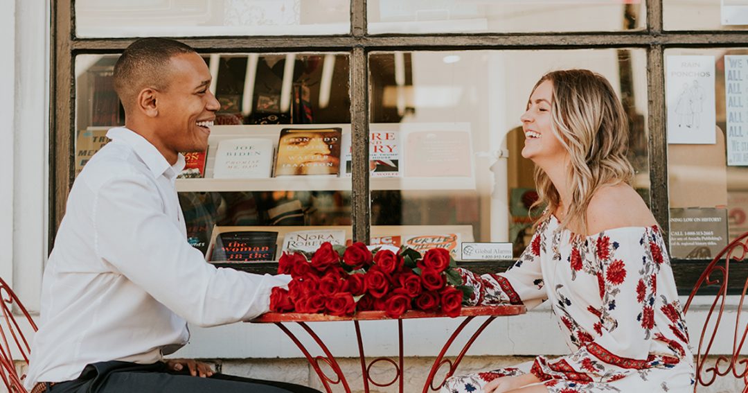 Couple Seated at a Cafe with a Bouquet of Red Roses Meaning Love on the Table