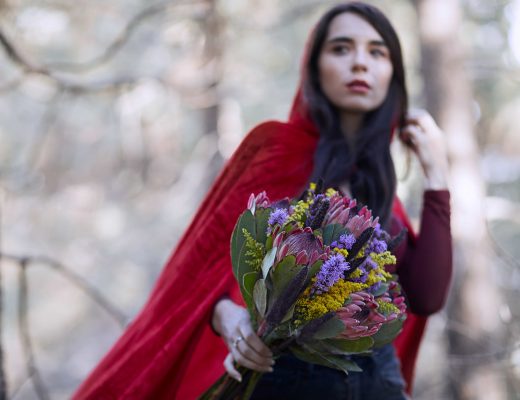 Woman wearing a red hood, holding a fall bouquet