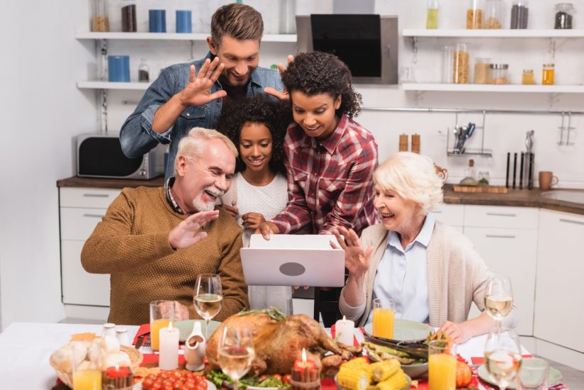 Family gathered around the table having a vide-conference during Thanksgiving