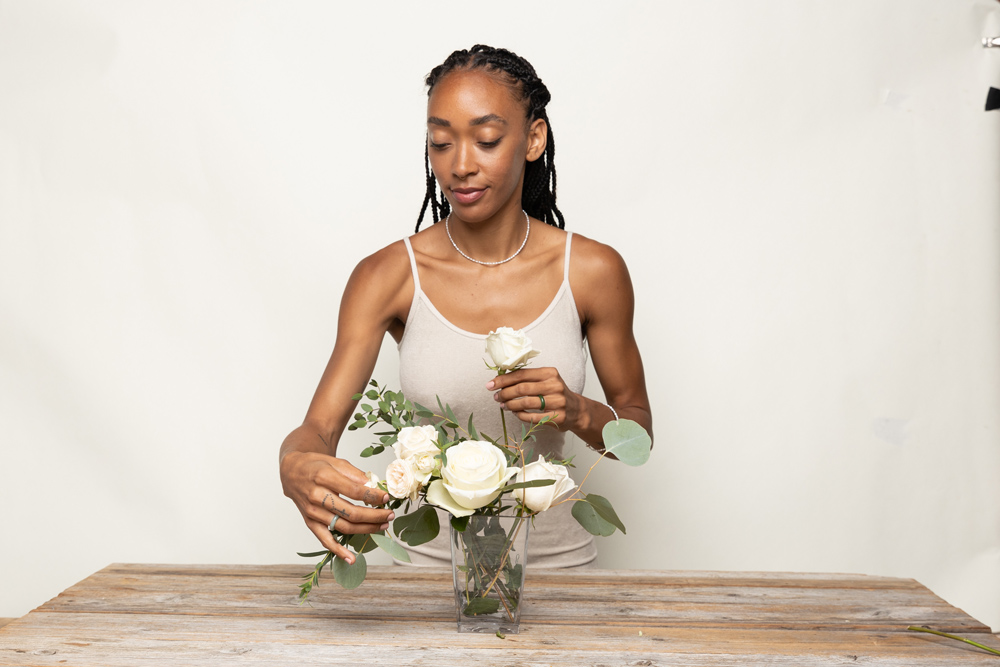 woman arranging white roses bouquet