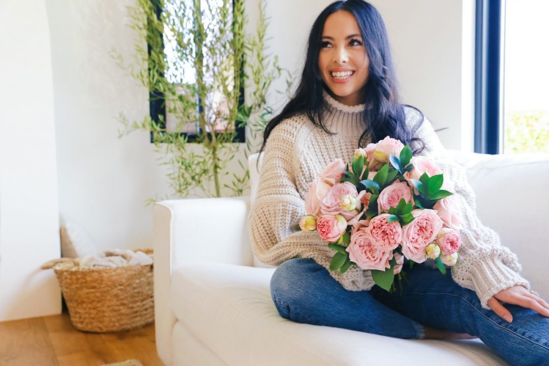 Woman on coach with valentine's day flowers.