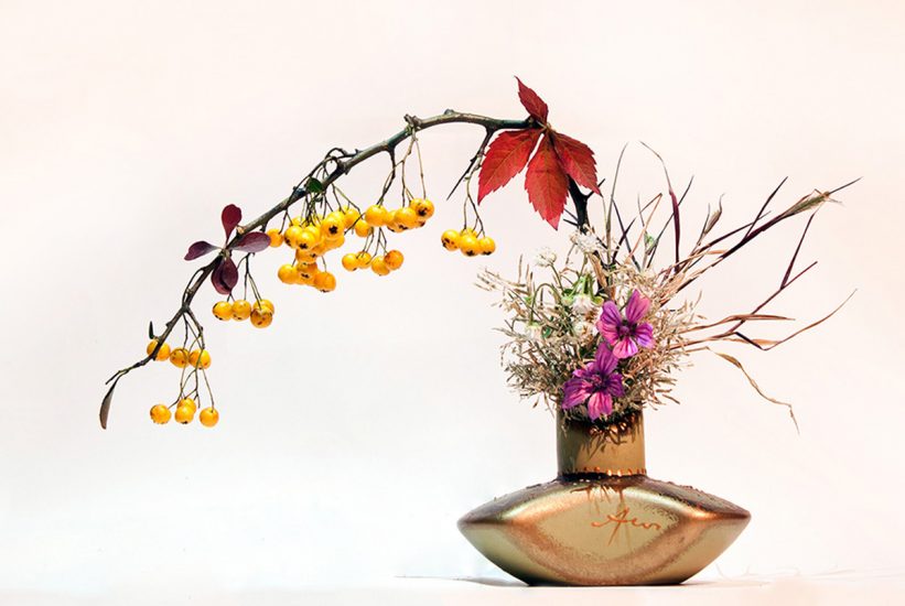 Ikebana arrangement with yellow fruit, purple flowers and red leaves