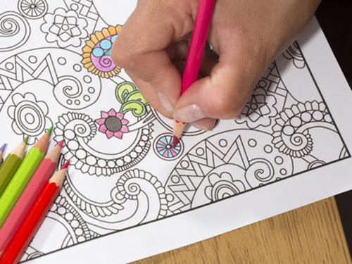 Person coloring in coloring book with pencils.