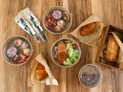 Counter with dishes of goof including fruit, sandwiches, and pastries.