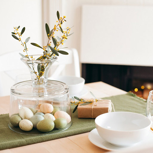 Flowering stems planted in a glass vase with Easter eggs on the bottom.
