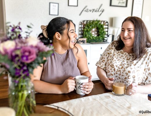 Two women having coffee with purple flowers on the table
