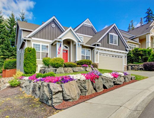 Home with flowering ground cover with a rock wall perimeter