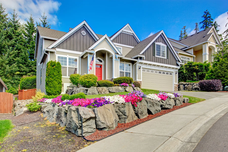 Home with flowering ground cover with a rock wall perimeter