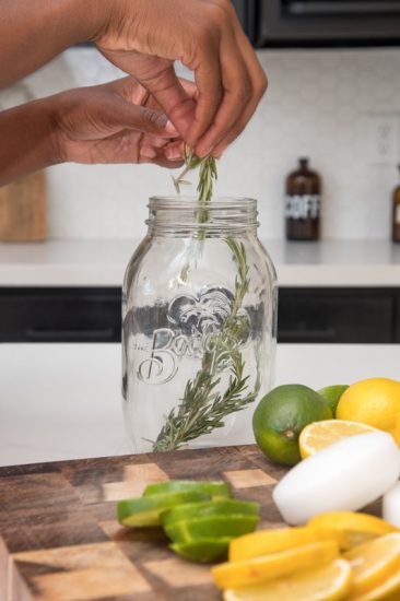 Dropping rosemary sprigs inside the mason jar
