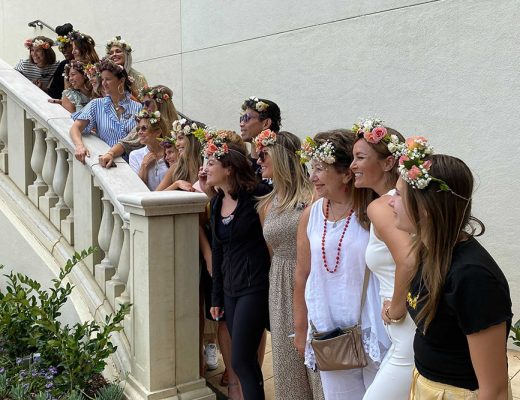 Group of people posing on outdoor stairs with flower crowns