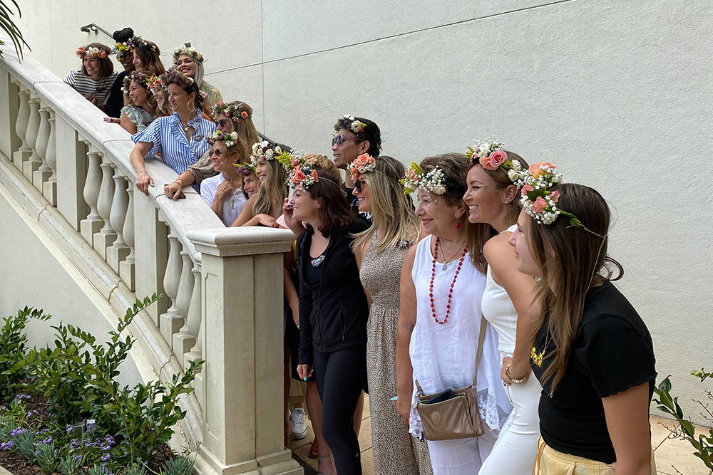Group of people posing on outdoor stairs with flower crowns