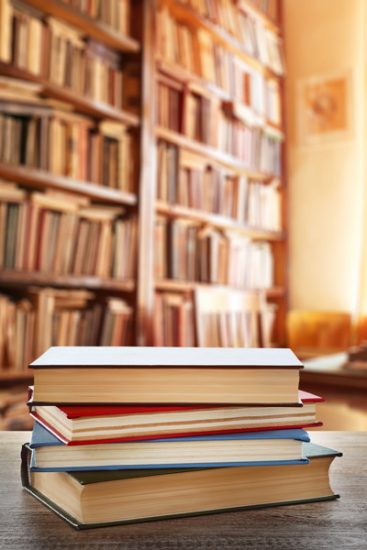 stack of books in library lit by sunlight