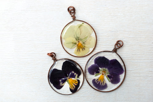 Handmade epoxy resin jewelry. pendant, violet flower in copper frame. dried flowers.