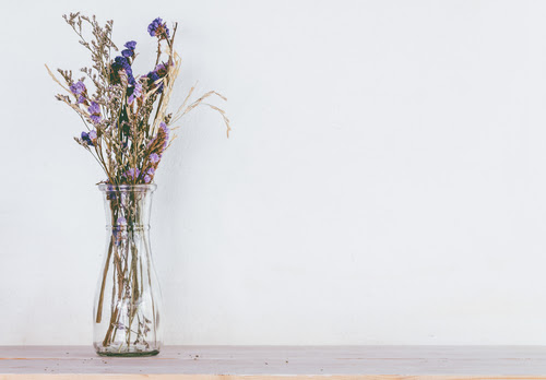 dried flower bouquet of purple in glass vase on wooden table
