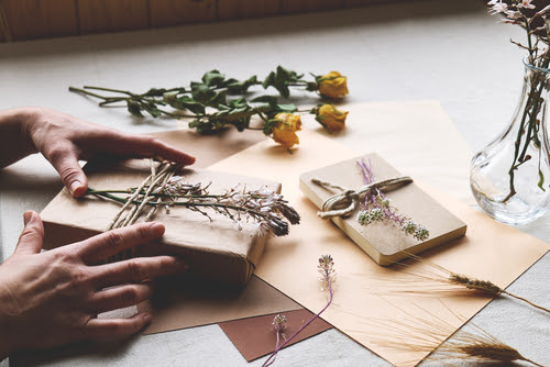 Dried flower hand made gift package with craft recycled paper and dried flowers on the table with linen tablecloth.