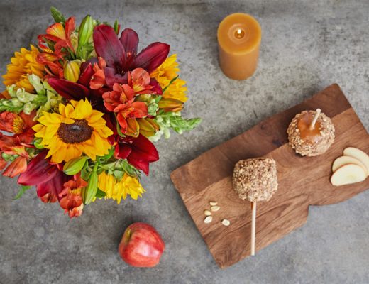 red, yellow, orange flower centerpiece with a candle and candy apples