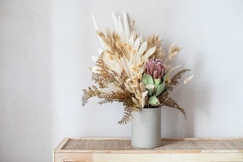 Minimalistic composition of dried flowers in cylindrical ceramic vase as home decoration.