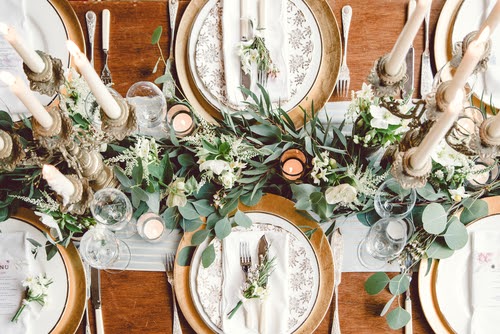 Aerial view of winter green garland on a wedding receptions head table with gold place setting and candelabra