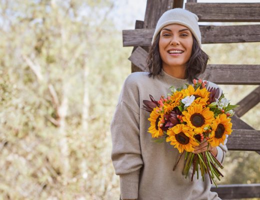 yellow sunflower bouquet for friendship held by woman in a beanie and sweater