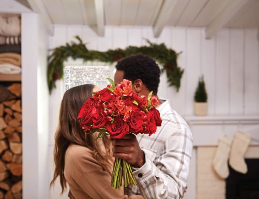 Man gifting woman bouquet of red flowers