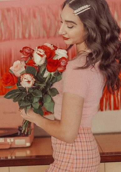 red, white, and peach valentine's bouquet held by woman in vintage outfit