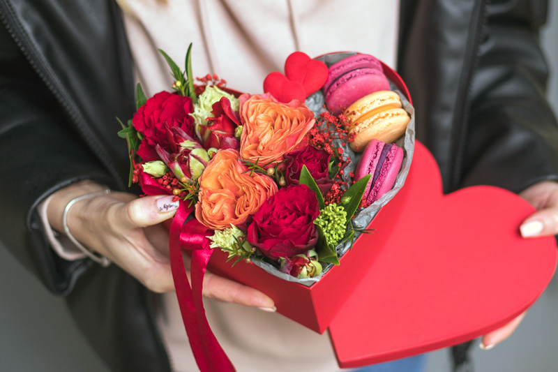 Red and orange flowers in a heart shaped hat box for valentines day
