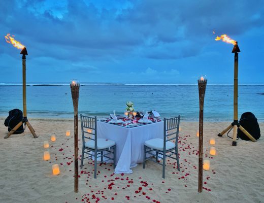 beach date with table torches, flower petals and dinner laid out