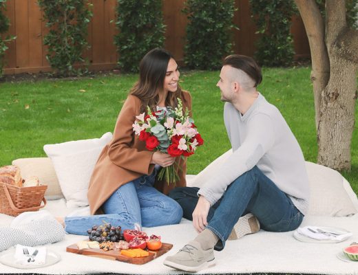 couple on blanket in park with flowers having a romantic picnic