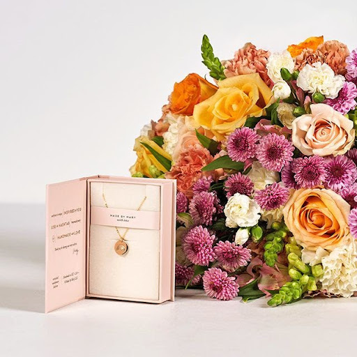 Multicolored bouquet in yellow, pink, peach, orange with a Kendra Scott neckalace
