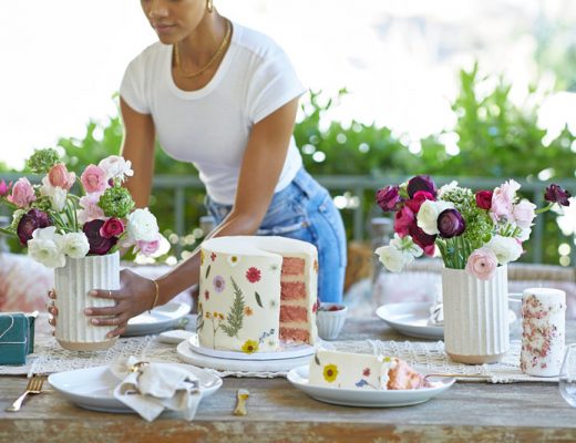 women setting table with cake, candles and flowers
