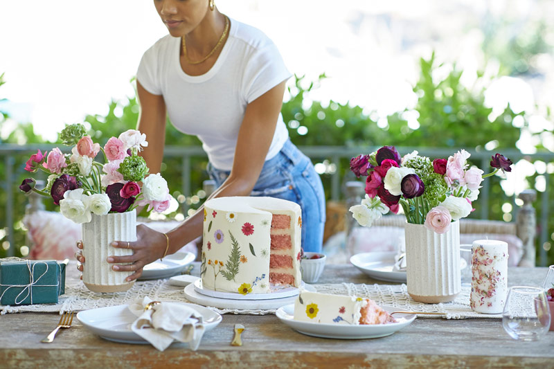 women setting table with cake, candles and flowers