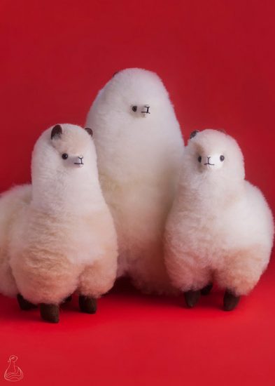 three white stuffed alpacas on red background