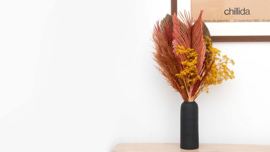copper colored dried flowers in a black vase
