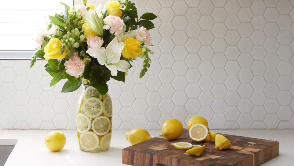 yellow and white flowers in a vase filled with lemon slices