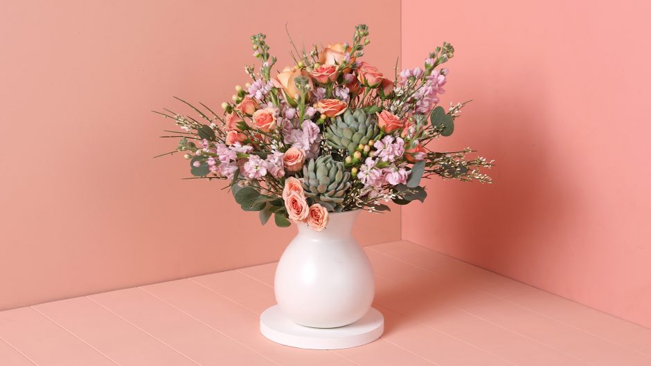 bouquet with succulents, pink roses and lavender flowers in a white artisan vase