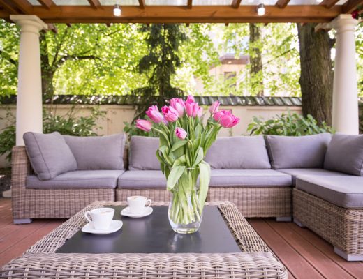 outdoor patio with tulips in a vase on a wicker table