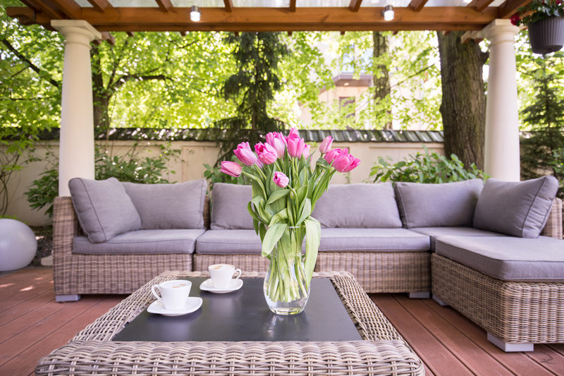 outdoor patio with tulips in a vase on a wicker table