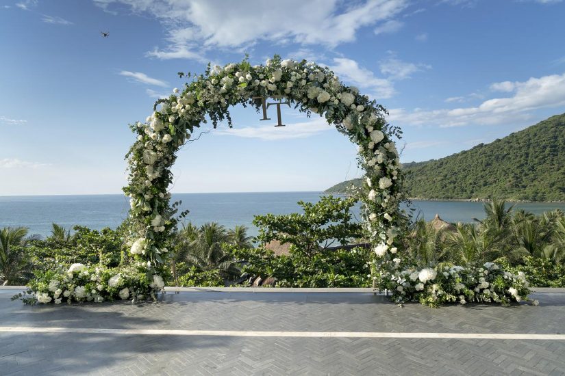 tall, round arch covered in greenery and white flowers