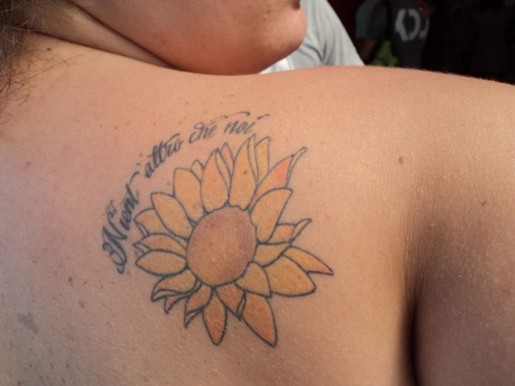 sunflower tattoo on the back of a person's right shoulder