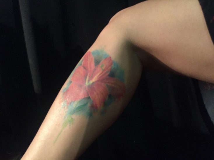 red hibiscus tattoo ln the side of a person's lower leg